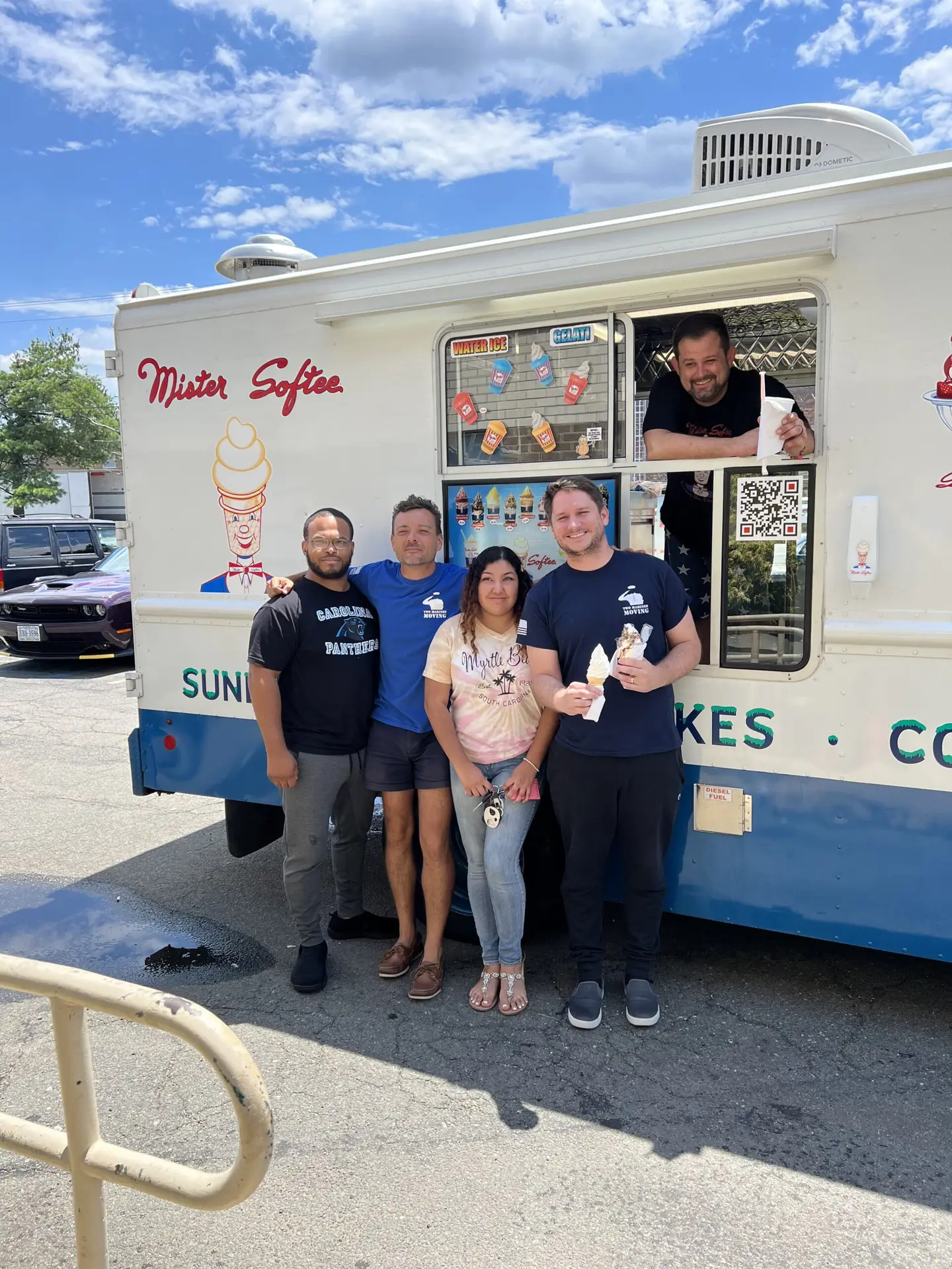 Group posing in front of a food truck on a sunny day.
